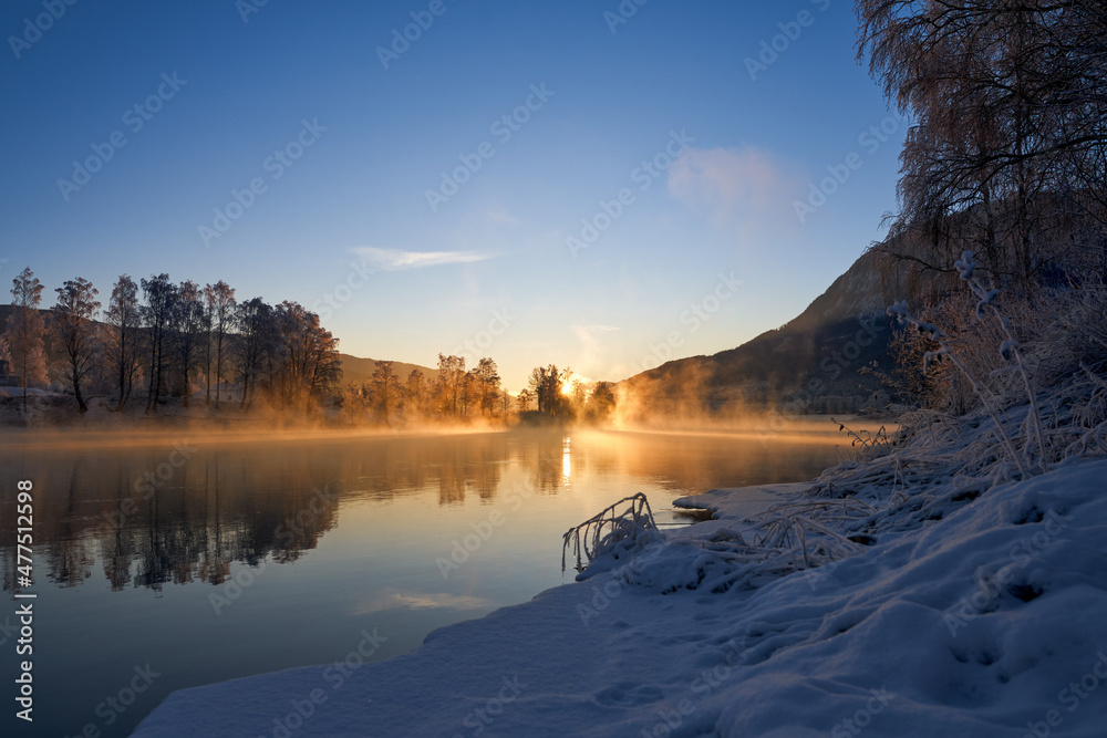 Sunrise over the river Hallingdalselva. Shot at Nesbyen, Norway. It is December and minus 20 degree outside. The water in the river is warmer than the air so therefor the smoke on the river. Frost. 
