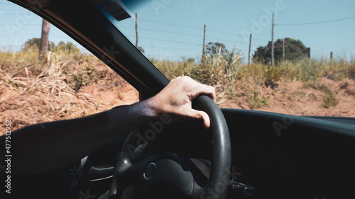 Mano sobre el volante de carro en carretera natural