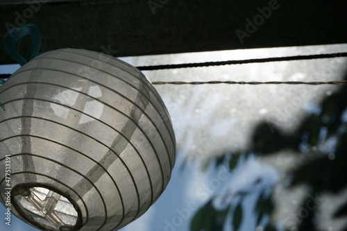 Fotografia Weiße rundförmige Laternenlampe aus Papier im Garten vor Himmel im Sommer