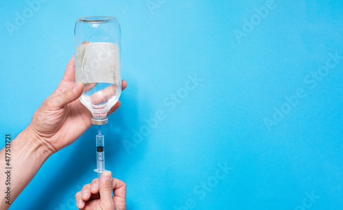 syringe with vaccine solution on the blue background photo