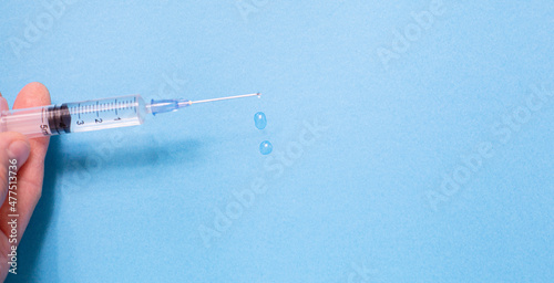 syringe with vaccine solution on the blue background photo