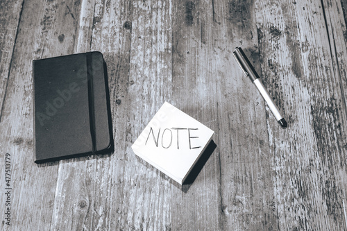 Flatlay from a wooden table with a blocknote and a pen. photo