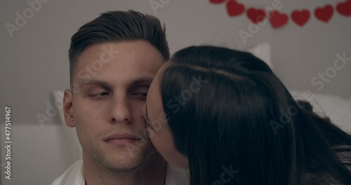 Young woman kissing her boyfriend at home. Valentines Day celebration