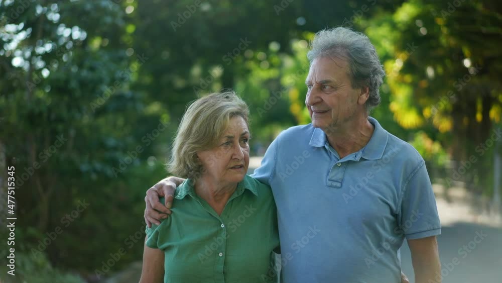 Pensive older couple walking during sunny day, 60s people Pensive older couple walking during sunny day, 60s people
