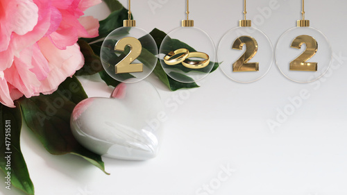 golden wedding rings glass bauble 2022 digits beautiful pink flower on green leaf and white glossy heart - copy space photo