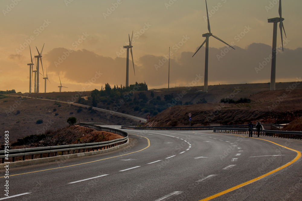 road going into the distance at sunset, windmills along the road