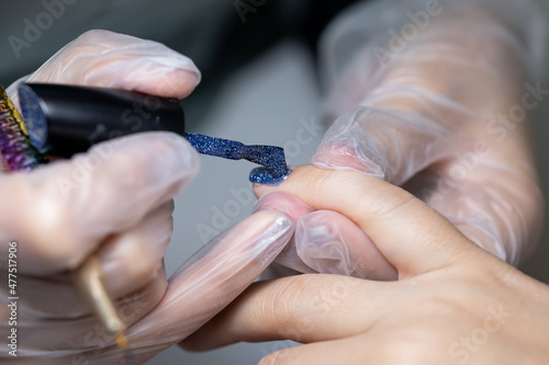 the manicure master applies the final layer of gel polish to the client s nail