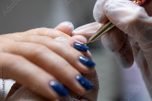 a close-up of the master applies a gel polish with a brush to the surface of the nail under the lamp glowing on them
