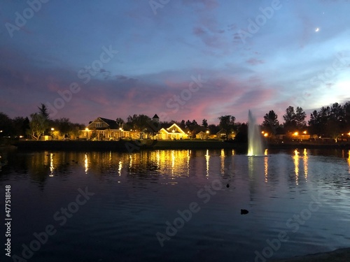 Lake house lights reflecting in the water with pastel clouds and sky.