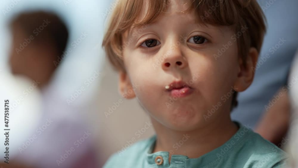 Portrait small boy waving hello while holding piece of bread chewing food Portrait small boy waving hello while holding piece of bread chewing food