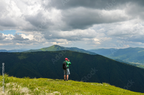 Nature photographer with backpack taking photos while hiking in the mountains. Travel photo lifestyle.