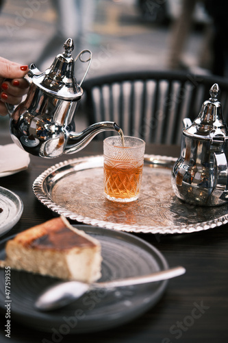 Fototapeta Naklejka Na Ścianę i Meble -  Woman serving tea on the terrace of an arabic teahouse. Accompanied with a cheese cake