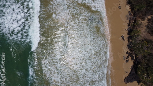 Ocean waves and sandy beach on sunny day. Aerial view