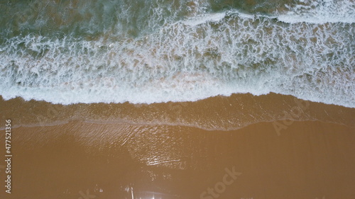 Ocean waves and sandy beach on sunny day. Aerial view