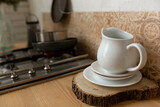 teapot on a saucer on a board cut wood. white tableware