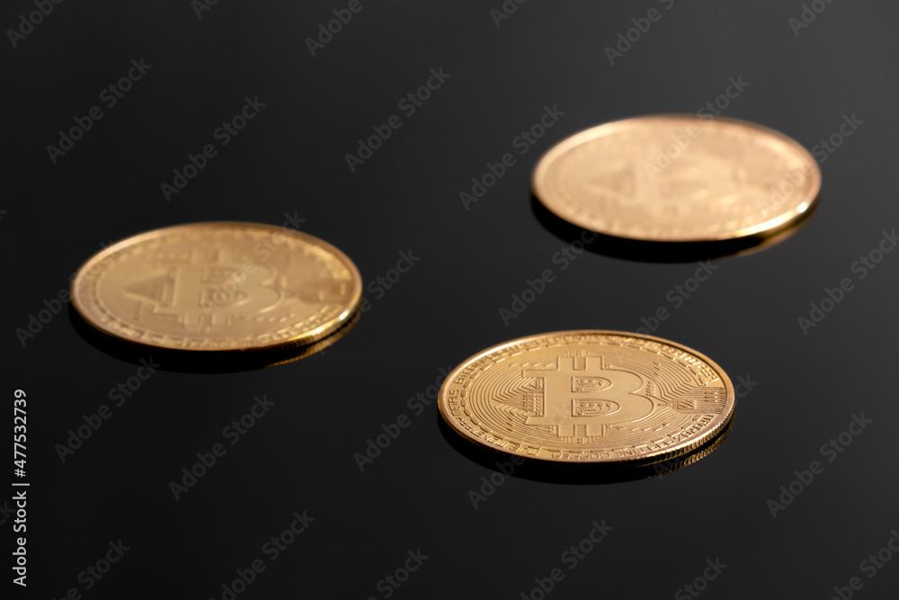 Detail studio shot of three golden bitcoins laying on black reflective surface. Concept for electronic money, crypto currency, blockchain investment, wealth, mining, financial markets. Detail studio shot of three golden bitcoins laying on black reflective surface. Concept for electronic money, crypto currency, blockchain investment, wealth, mining, financial markets.