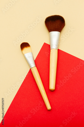 Flat lay composition of makeup brushes on yellow and beige background. Concelear brush and highlighting brush.