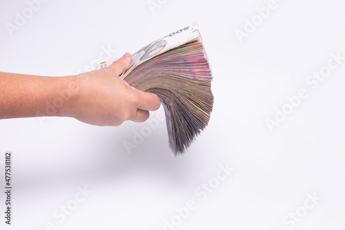 a thick wad of cash in his hand on a white background.