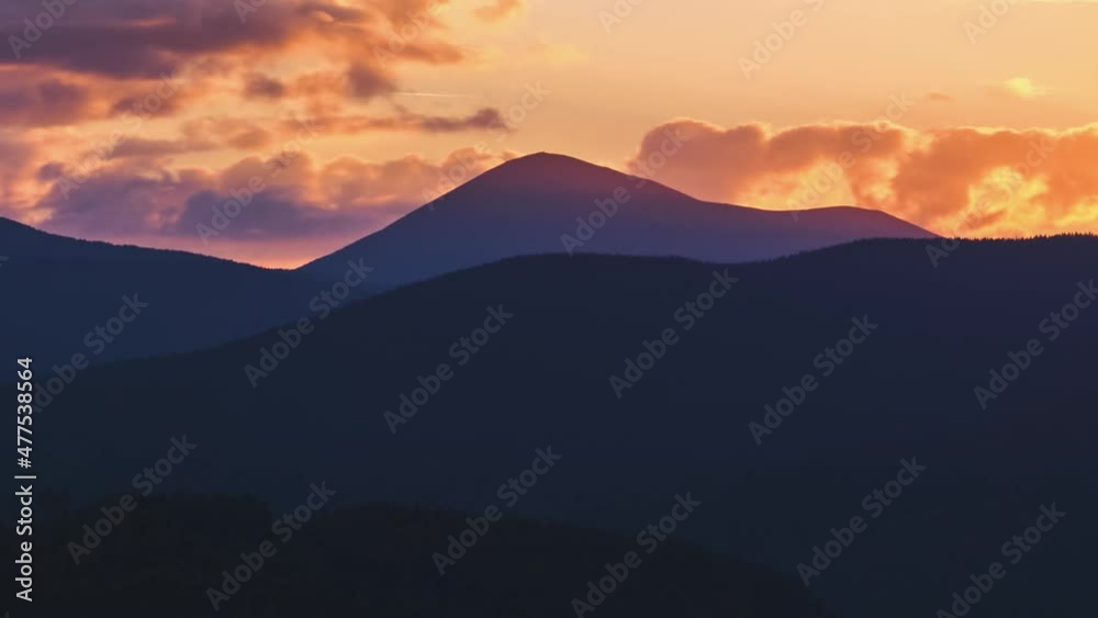 Beautiful evening panoramic landscape with bright setting sun over distant mountain peaks at sunset Beautiful evening panoramic landscape with bright setting sun over distant mountain peaks at sunset