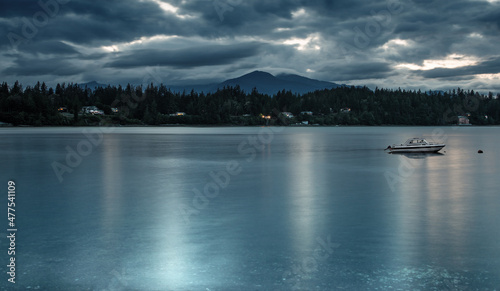 dark blue water and skies with olympic mountains and speedboat photo