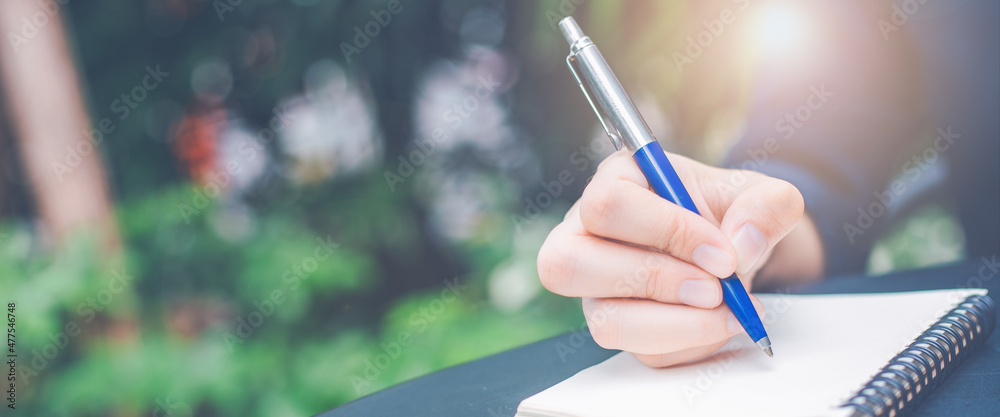 Business woman hand writing on a notepad with a pen in the office.