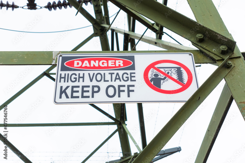Obraz premium Photograph of a safety sign a large steel electrical transmission tower