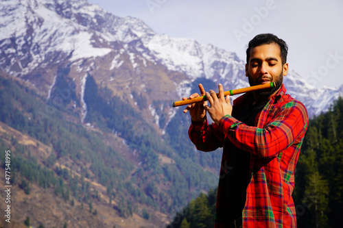 bansuri indian instrument Young boy playing bansuri Indian flute in mountains photo
