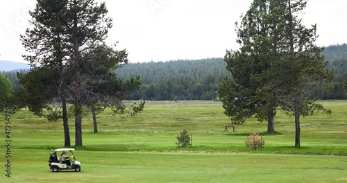 Golfer Driving Golf Cart With Airplane Take Off At Sunriver Airport In United States Of America. - wide shot photo