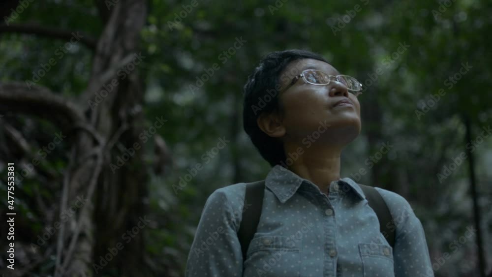 Portrait Asian female tourist is looking for direction and pathway to walk out of the forest in the dusk. Solo camping in the jungle. Travel explorer in the wildness area. Portrait Asian female tourist is looking for direction and pathway to walk out of the forest in the dusk. Solo camping in the jungle. Travel explorer in the wildness area.