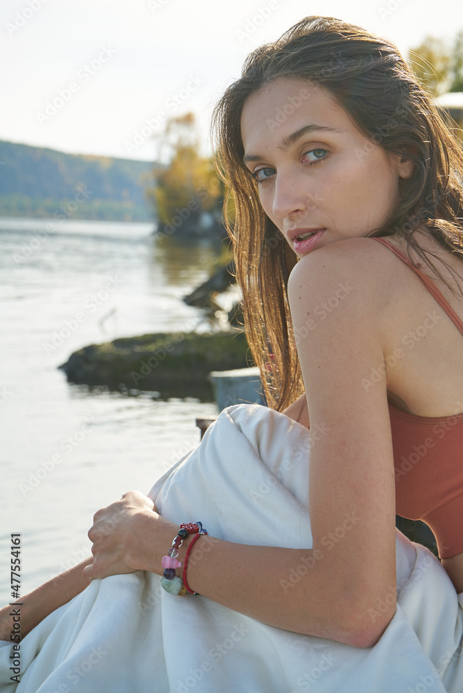 A young attractive woman of model appearance rests under a blanket on a pier. long hair. High quality photo A young attractive woman of model appearance rests under a blanket on a pier. long hair. High quality photo