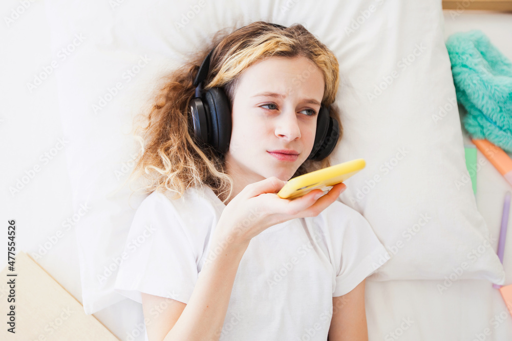 the girl is a sad child with headphones and a phone the girl is a sad child with headphones and a phone