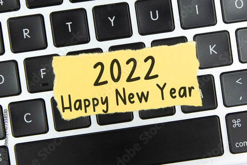 Text "2022 Happy New Year" on torn paper on top of keyboard