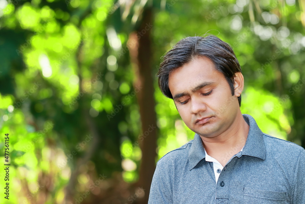 An Indian young adult boy looking down and thinking and thinking about something An Indian young adult boy looking down and thinking and thinking about something