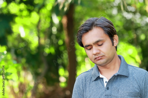 An Indian young adult boy looking down and thinking and thinking about something
