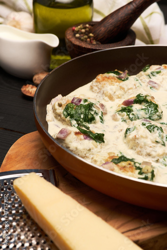 Delicious small meatballs with spinach in a creamy sauce in the frying pan