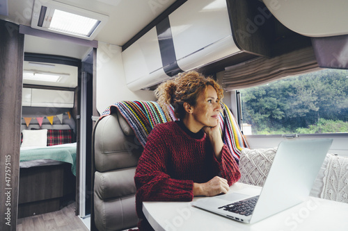 Canvastavla Adult woman use laptop computer inside a camper van recreational vehicle sitting at the table with bedroom in background and nature park outside the windos