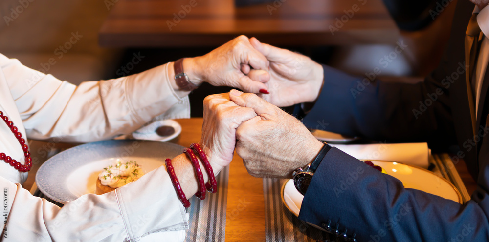 Elderly couple holding hands together during the dinner Elderly couple holding hands together during the dinner