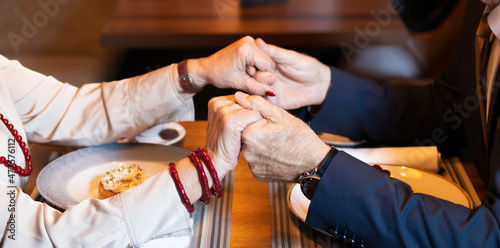 Elderly couple holding hands together during the dinner