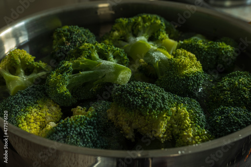 Frozen green broccoli florets inside pan casserole ready for boiling closup