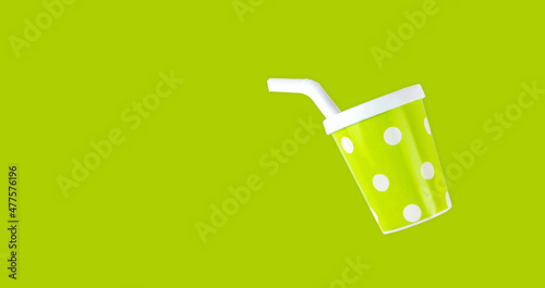 Plastic toy glass with straw on green background. Creative summer minimalistic background.