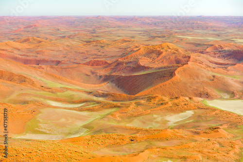 A horizontal aerial shot from an aeroplane of the Namibian desert landscape with endless orange sand dunes, Africa