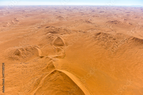 A barren horizontal aerial shot of golden sand dunes from an aeroplane of the Namibian desert landscape 