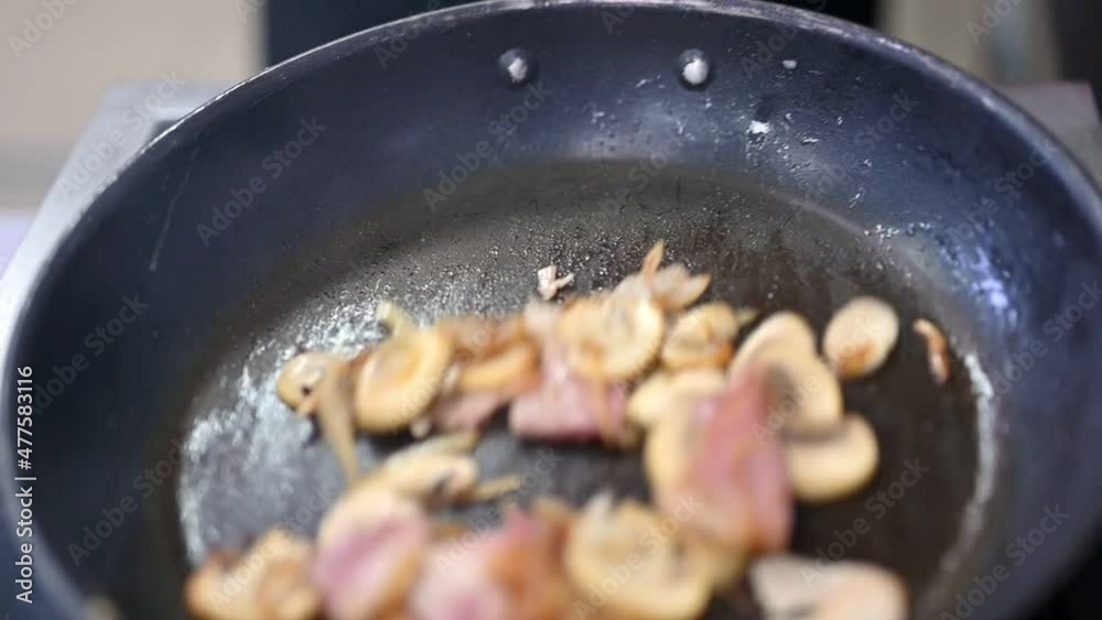 Mushrooms with bacon and onion on frying pan