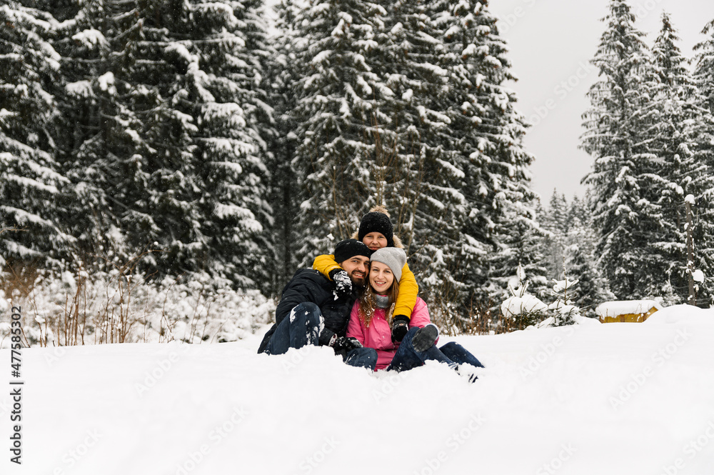 Happy family have fun in winter forest and looking at camera. Mother, father and son playing with snow. Family Christmas concept. Enjoying spending time together