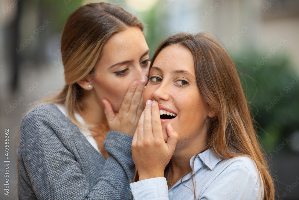Beautiful woman whispers to her mate shocking news outdoors Beautiful woman whispers to her mate shocking news outdoors