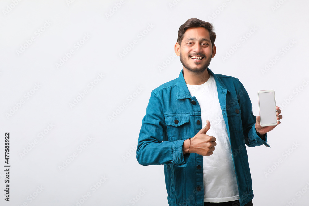 Young indian man showing smartphone screen on white background. Young indian man showing smartphone screen on white background.