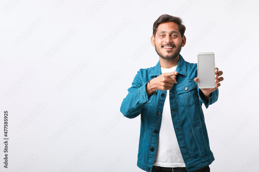 Young indian man showing smartphone screen on white background. Young indian man showing smartphone screen on white background.