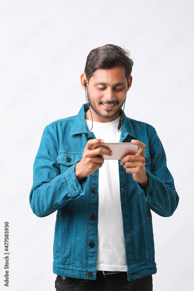 Young indian man using smartphone and giving expression on white background. Young indian man using smartphone and giving expression on white background.