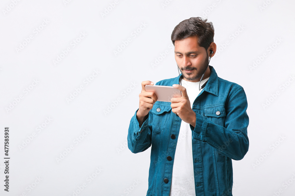 Young indian man using smartphone and giving expression on white background. Young indian man using smartphone and giving expression on white background.