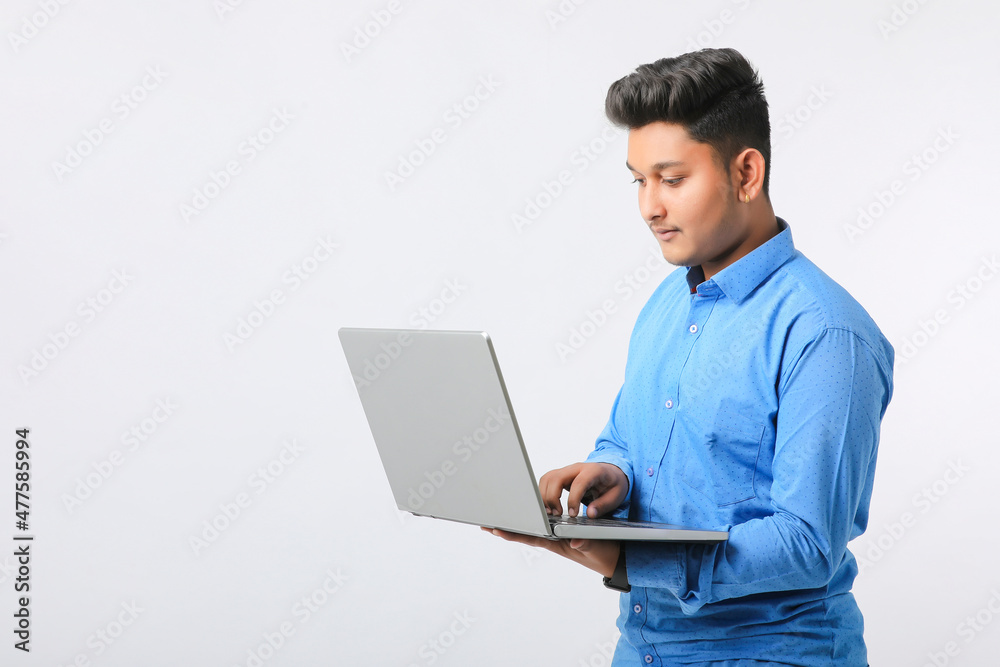 Young indian man using laptop over white background.